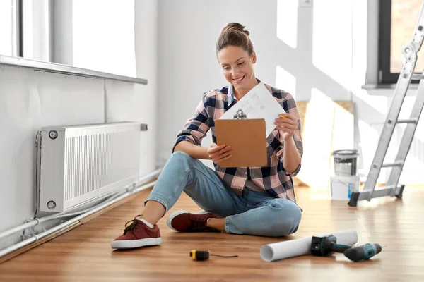 Woman with clipboard sitting on floor at home — Stock Photo, Image