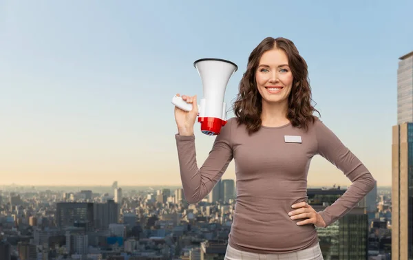 Assistente de loja feminino feliz com megafone na cidade — Fotografia de Stock