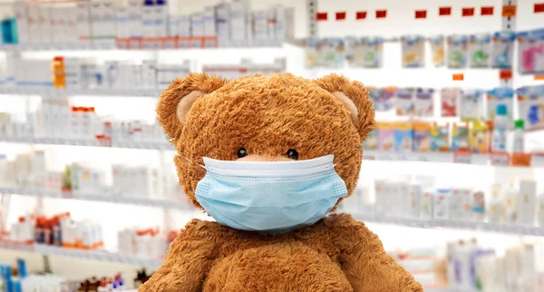 Medvídek hračka v lékařské masce v lékárně — Stock fotografie