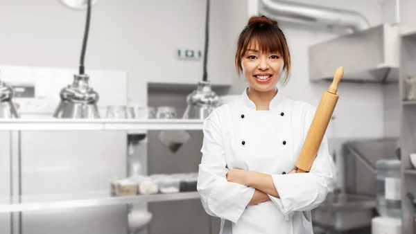 Vrouwelijke chef of bakker met deegroller op keuken — Stockfoto