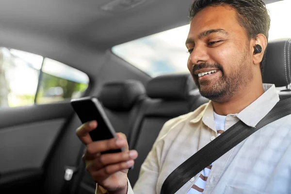 Passagerare med hörlurar och mobiltelefon i taxibil — Stockfoto