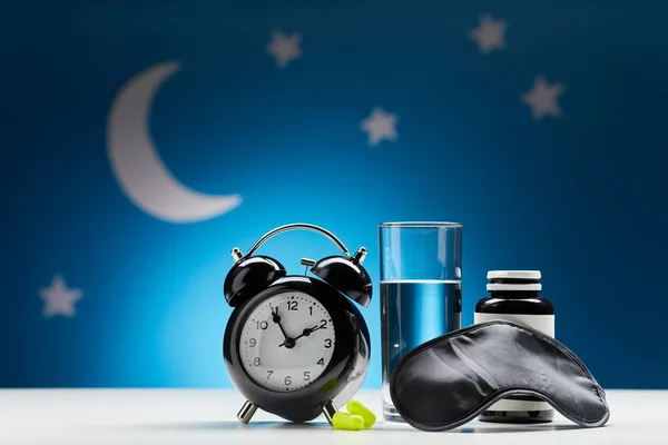 alarm clock, glass of water and eye sleeping mask