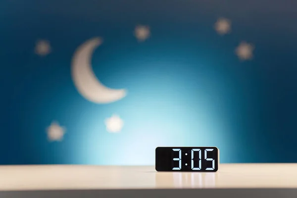 Alarm clock on table over night background — Stockfoto