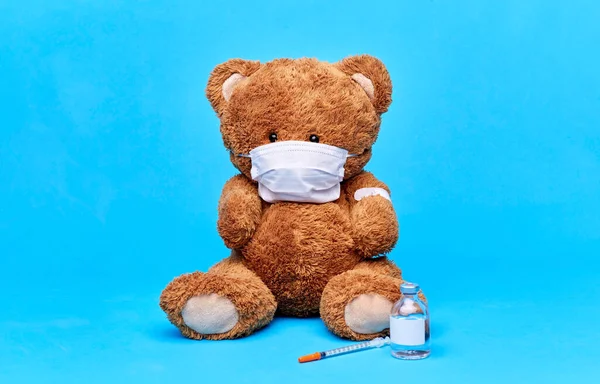 Nalle leksak i mask med vaccin och spruta — Stockfoto