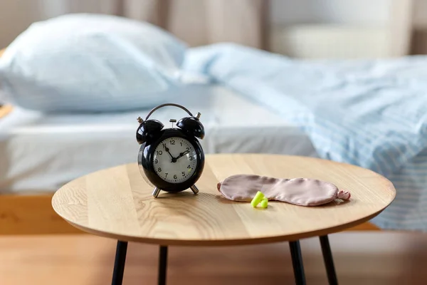 Alarm clock, earplugs and sleeping mask on table — Fotografia de Stock