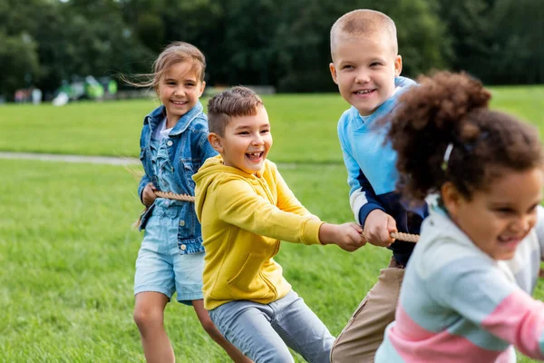 Niños felices jugando tirón de juego de guerra en el parque — Foto de Stock