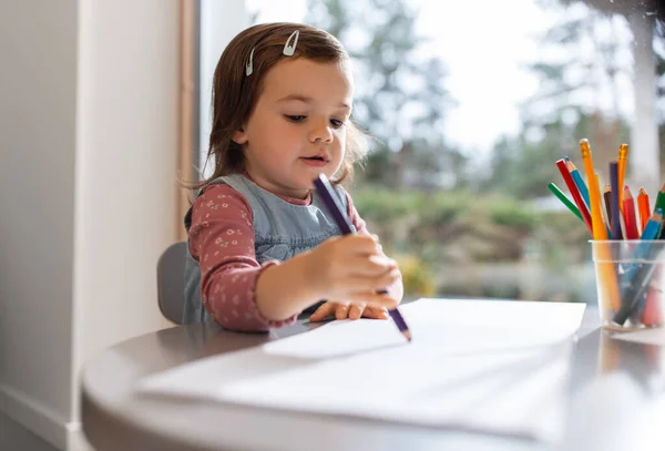 Маленька дівчинка з розмальовками олівцями малює вдома — стокове фото