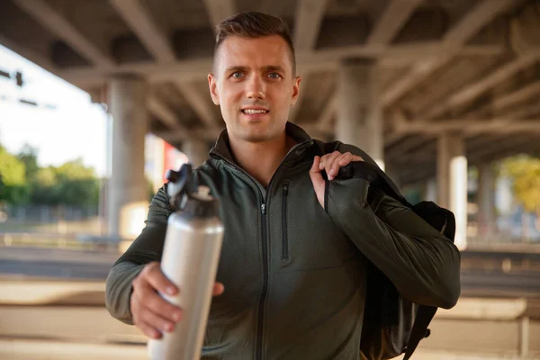 Smiling sportsman with bag and bottle outdoors — Fotografia de Stock