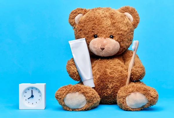 Teddybär mit Zahnbürste, Zahnpasta und Uhr Stockbild