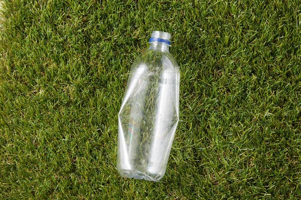 Boş kullanılmış plastik şişeyi çimlerin üzerine kapatın. — Stok fotoğraf