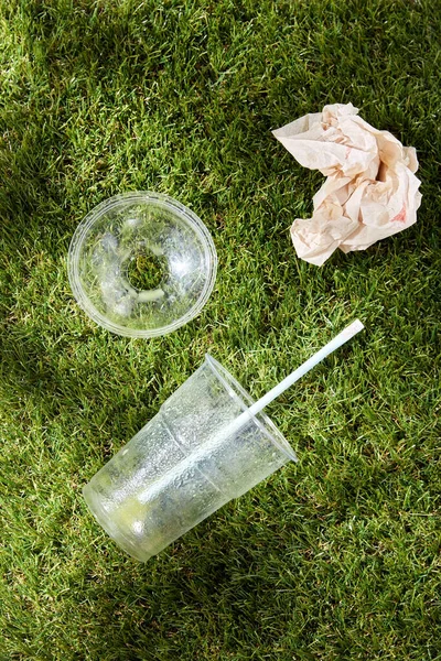 A használt eldobható műanyag csésze közelsége a füvön — Stock Fotó
