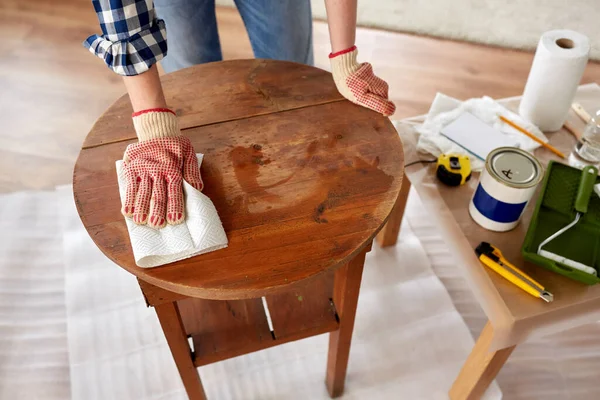 Vrouw schoonmaken van oude tafel oppervlak met papier weefsel — Stockfoto