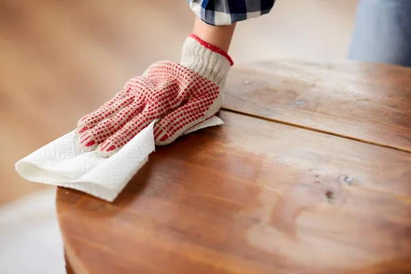 Vrouw schoonmaken van oude tafel oppervlak met papier weefsel — Stockfoto