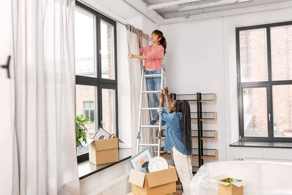 Kvinna på stege hängande gardiner hemma — Stockfoto