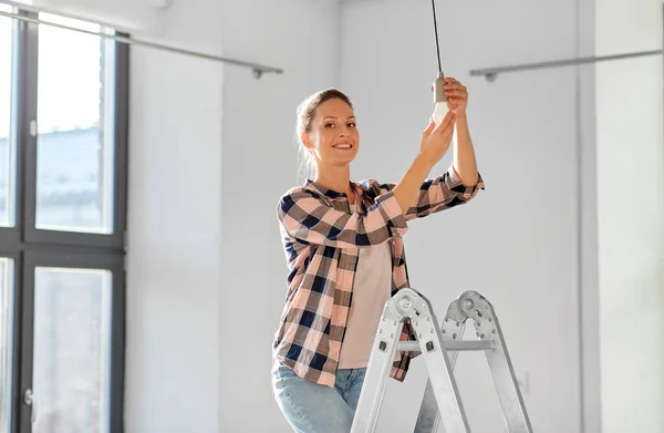 Mujer que cambia la bombilla en el nuevo hogar — Foto de Stock