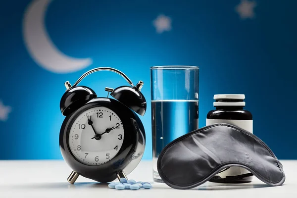Despertador, vidro de água e comprimidos para dormir — Fotografia de Stock