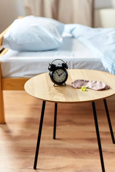 Wekker, oordopjes en slaapmasker op tafel — Stockfoto