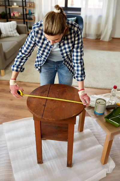 Žena s pravítkem měřící stůl pro renovaci — Stock fotografie