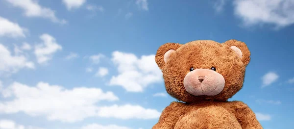 Brown teddy bear toy over blue sky background — стоковое фото