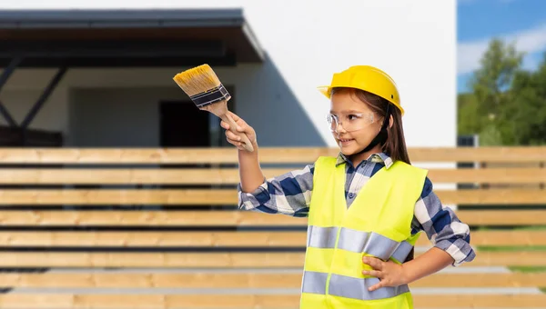 Meisje in helm en veiligheidsvest met penseel — Stockfoto