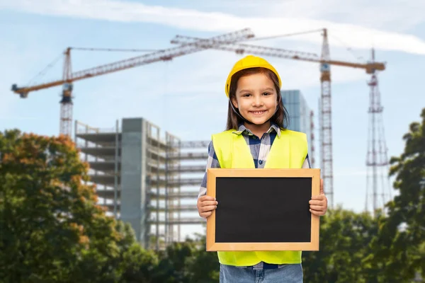 Little girl in construction helmet with chalkboard — Stock Photo, Image