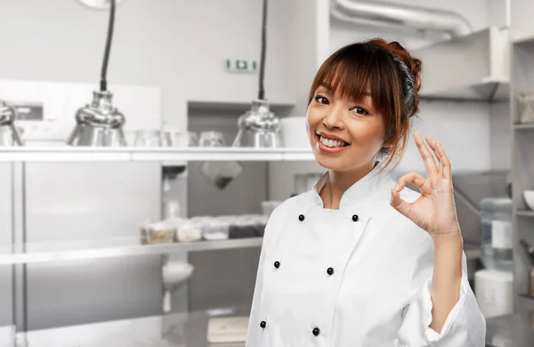 Smiling female chef showing ok gesture at kitchen — стоковое фото