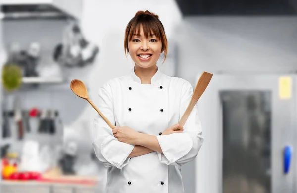 Happy female chef with wooden spoon on kitchen — Stockfoto