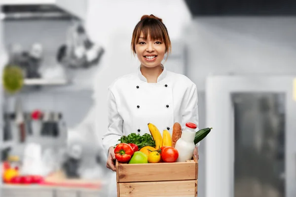 Happy female chef with food in box on kitchen — ストック写真