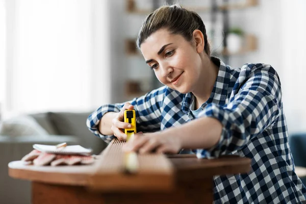 Mujer con regla que mide tablero de madera —  Fotos de Stock