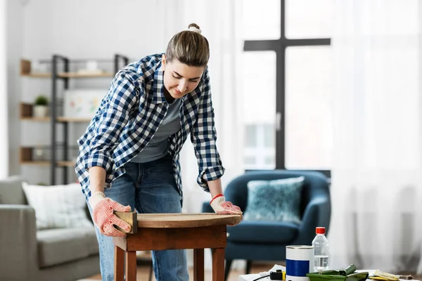 Woman sanding old round wooden table with sponge — Stock Photo, Image