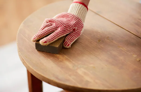 Yaşlı kadın süngerle ahşap masayı zımparalıyor. — Stok fotoğraf