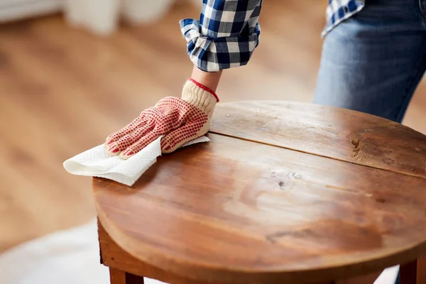 Mujer limpiando la superficie de la mesa vieja con papel — Foto de Stock