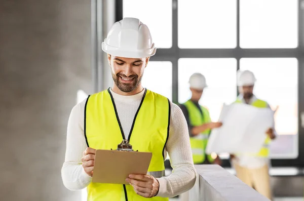 Architekt mit Helm und Klemmbrett im Büro — Stockfoto