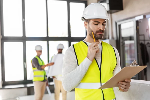 Architekt mit Helm und Klemmbrett im Büro — Stockfoto