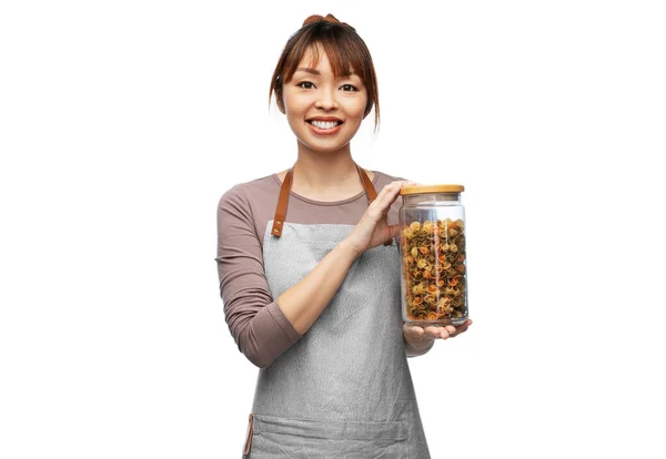 Usmívající se žena v zástěře drží sklenici s těstovinami — Stock fotografie