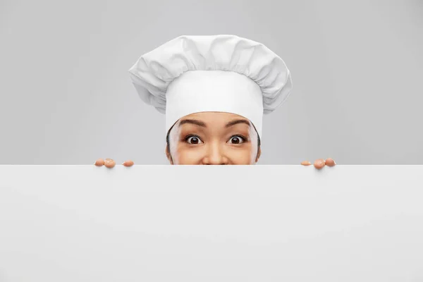 Kvinnlig kock kikar ut bakom vit bräda — Stockfoto