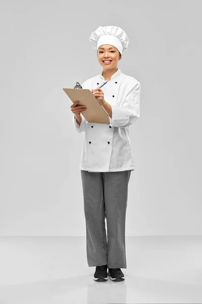 Sırıtkan kadın aşçı, kağıt ve kalemle — Stok fotoğraf