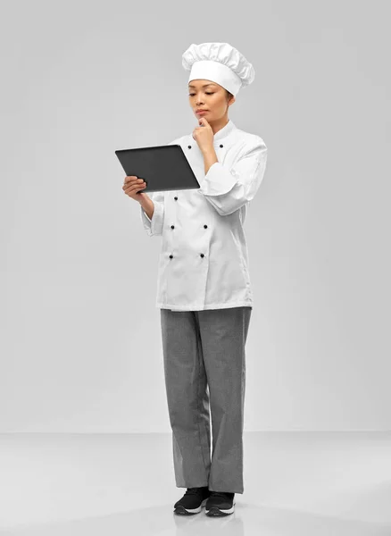 Thinking female chef with tablet computer — Stockfoto