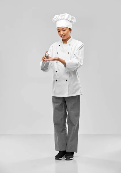 Female chef applying hand sanitizer or liquid soap — Stockfoto