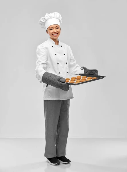 Happy female chef with cookies on oven tray — Stock Photo, Image