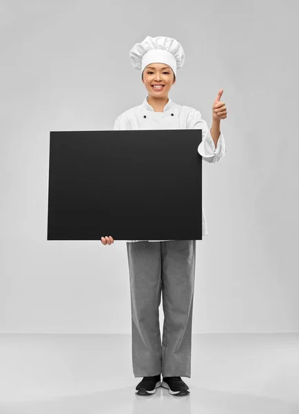 Усміхнена жінка-кухарка тримає чорну крейду — стокове фото
