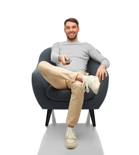 Happy man with tv remote control sitting in chair — 图库照片