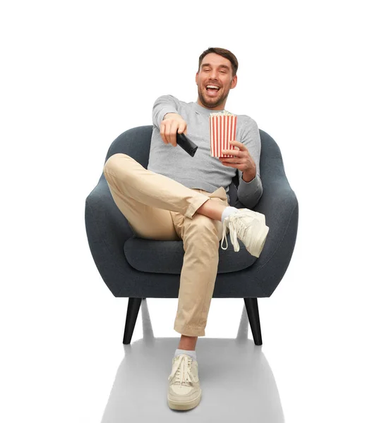 Man with tv remote and popcorn sitting in chair — 图库照片