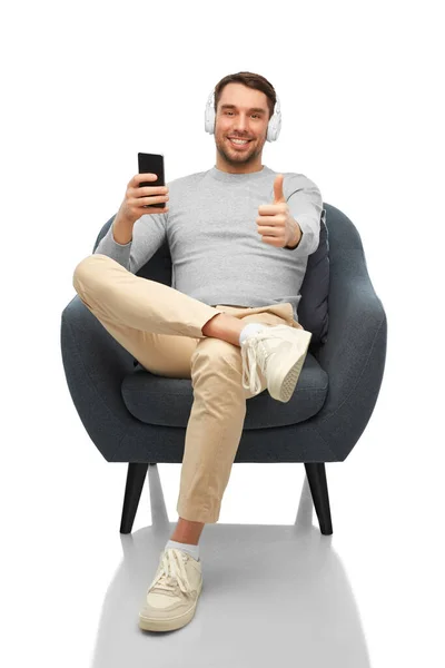 Man with phone and headphones showing thumbs up — 图库照片