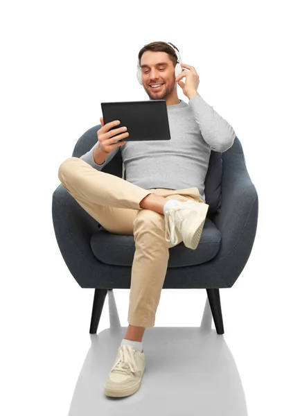 Man with headphones and tablet pc sitting in chair — Stockfoto