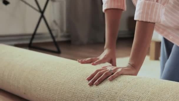 Joven mujer desplegable alfombra en casa — Vídeo de stock