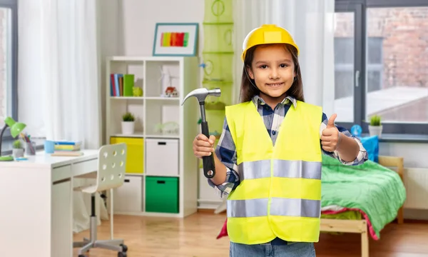 Happy girl with hammer showing thumbs up at home — Stockfoto