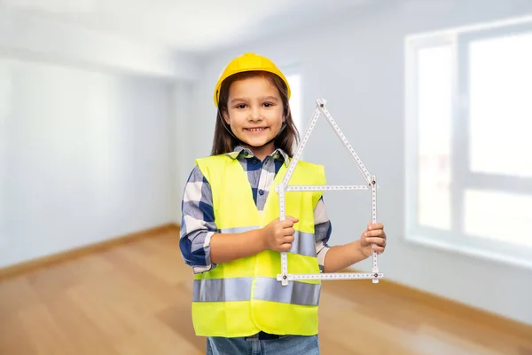 Klein meisje in helm met liniaal in de vorm van huis — Stockfoto