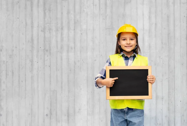 Маленькая девочка в строительном шлеме с доской — стоковое фото