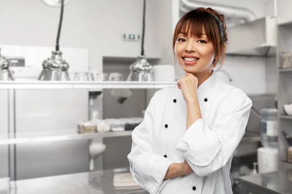 Smiling female chef in white jacket at kitchen — Fotografia de Stock